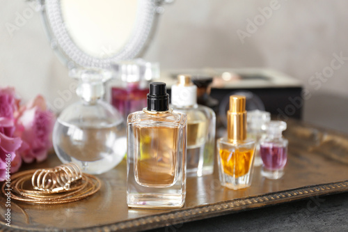 Metal tray with bottles of perfume on table