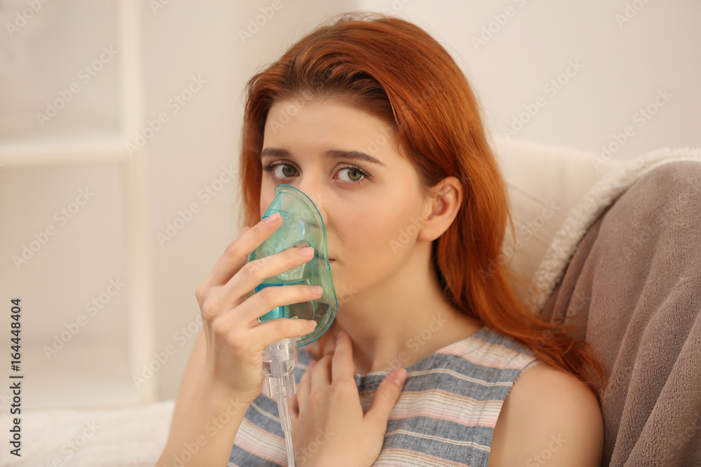 Young woman using nebulizer for asthma and respiratory diseases at home Young woman using nebulizer for asthma and respiratory diseases at home