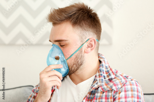 Young man using nebulizer f...