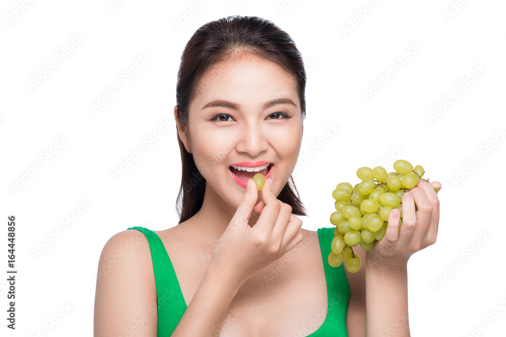 Young beautiful asian woman eating fresh grapes isolated on white background Young beautiful asian woman eating fresh grapes isolated on white background