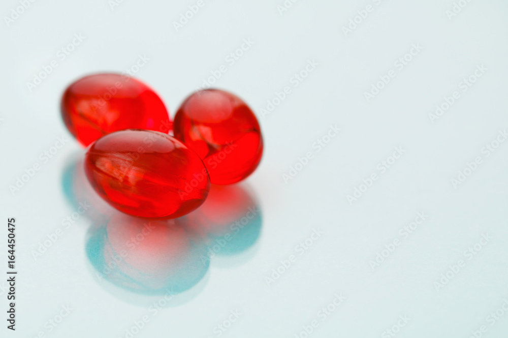 Close-up of red painkiller pills on a blue background. Close-up of red painkiller pills on a blue background.