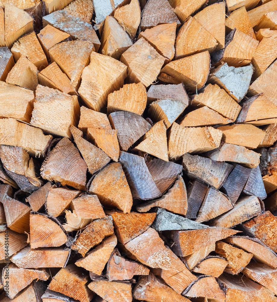 Background of dry chopped firewood logs stacked up on top of each other in a pile in winter Background of dry chopped firewood logs stacked up on top of each other in a pile in winter