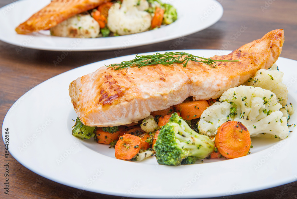 salmon fillet on a bed of broccoli, cauliflower and carrots salmon fillet on a bed of broccoli, cauliflower and carrots