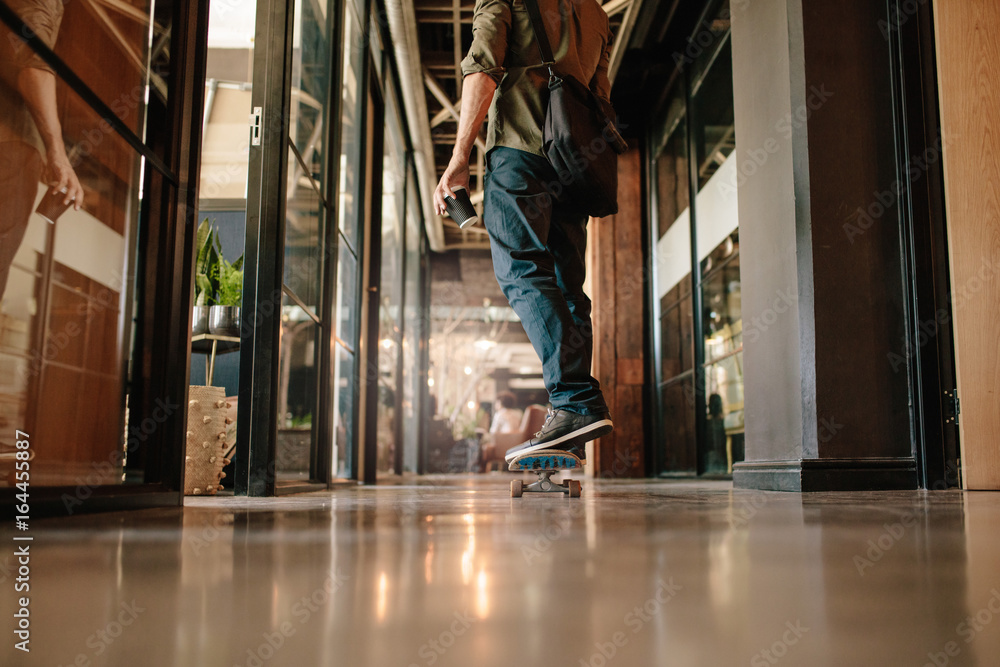 Fototapeta premium Young man skating through his startup office