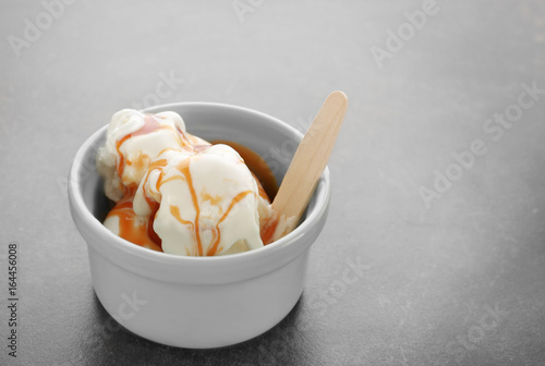 Bowl with vanilla ice cream and caramel sauce on table