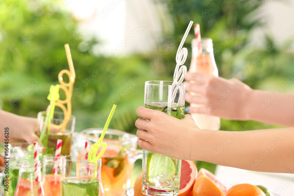 Fototapeta premium Friends cheering with glasses of different kinds of lemonade on picnic