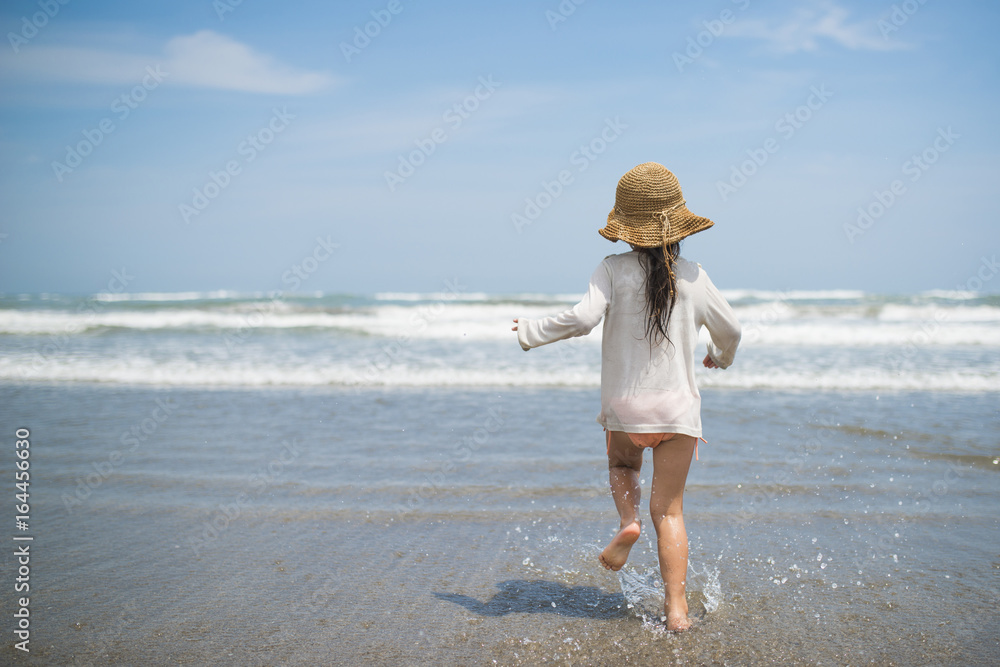 Happy little girl playing on the beach