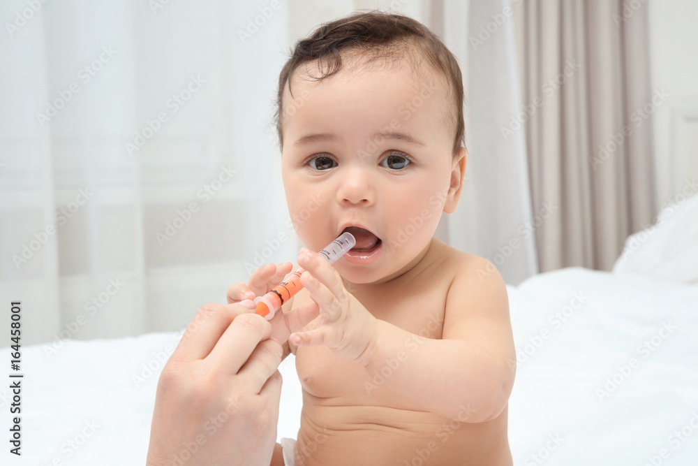 Mother using special syringe to give medicine to her child at home. Health care concept Mother using special syringe to give medicine to her child at home. Health care concept