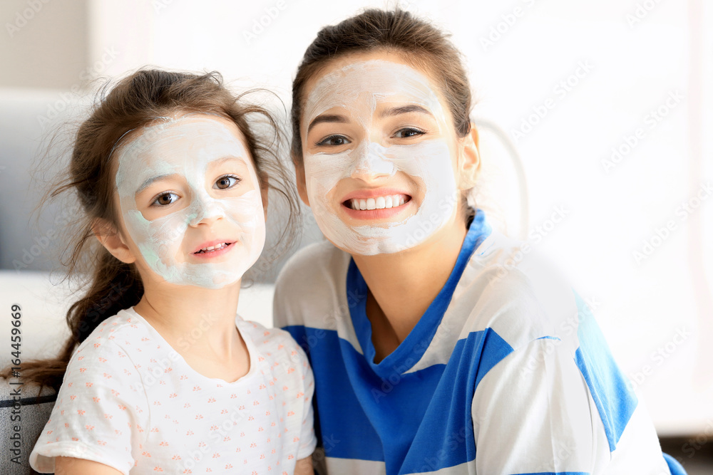 Young woman and her little daughter with facial masks at home Young woman and her little daughter with facial masks at home