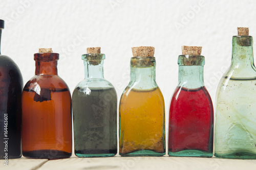 Many antique glass bottles with colored liquids. For the pharmacy, oil, cosmetics.