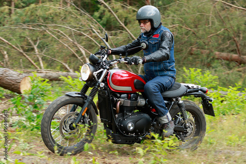Man in grey helmet riding the red motorcycle in the forest