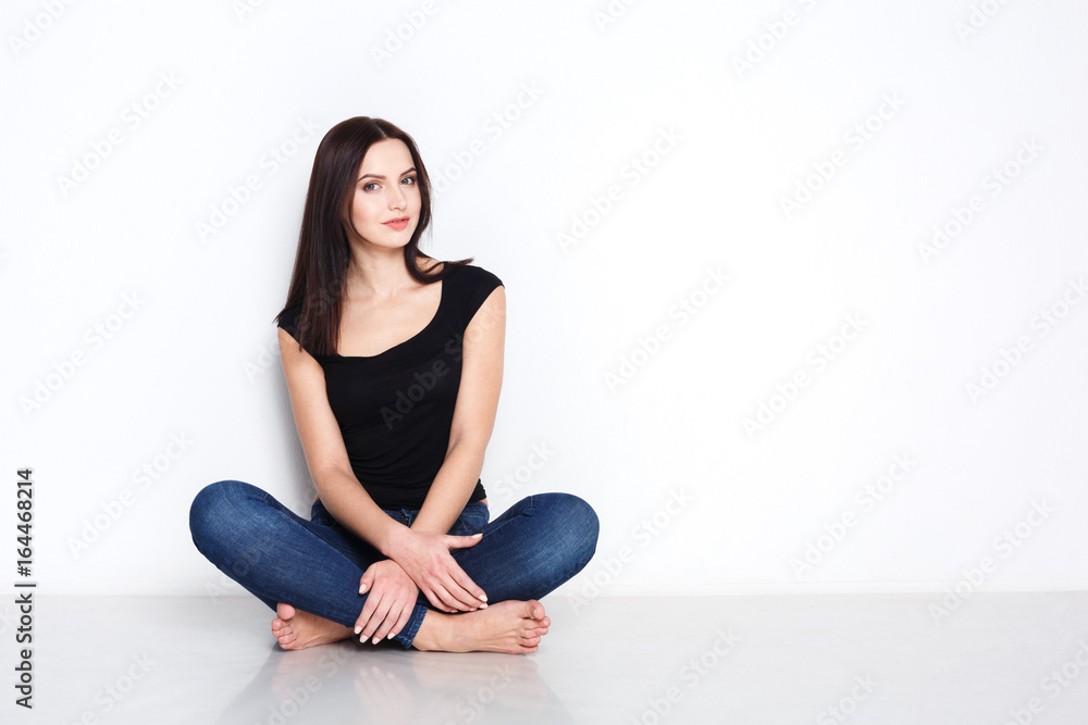 Barefoot woman in casual wear sitting on floor