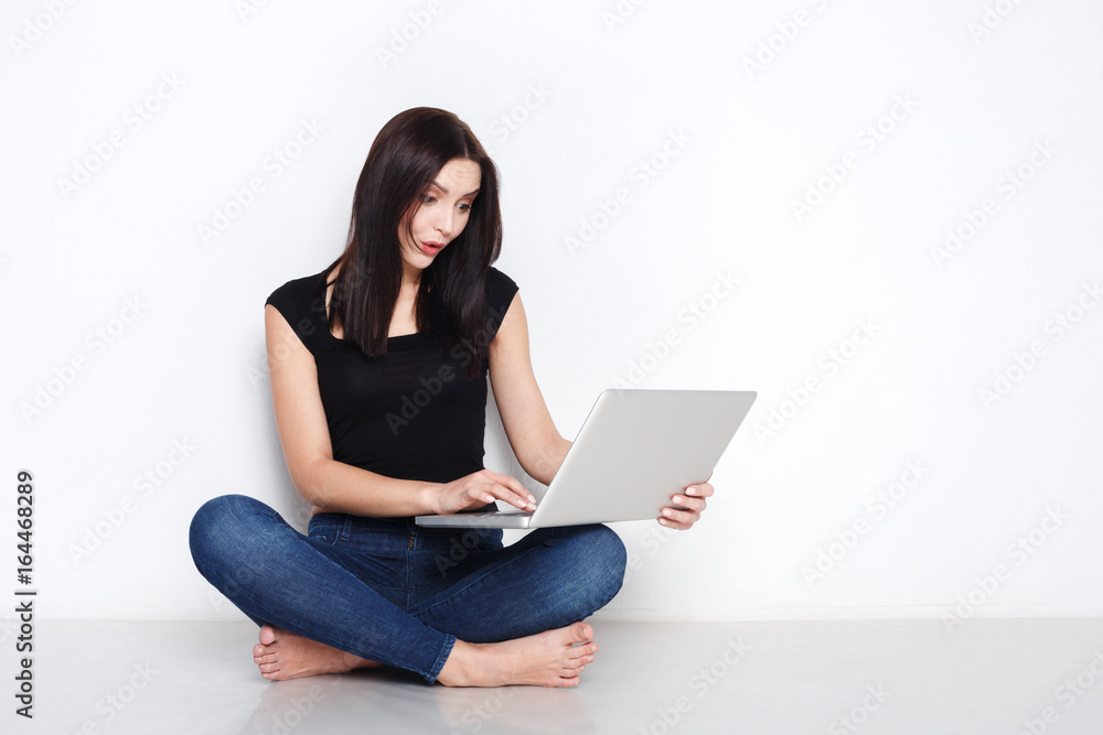 Fototapeta premium Woman using laptop sitting on the studio floor