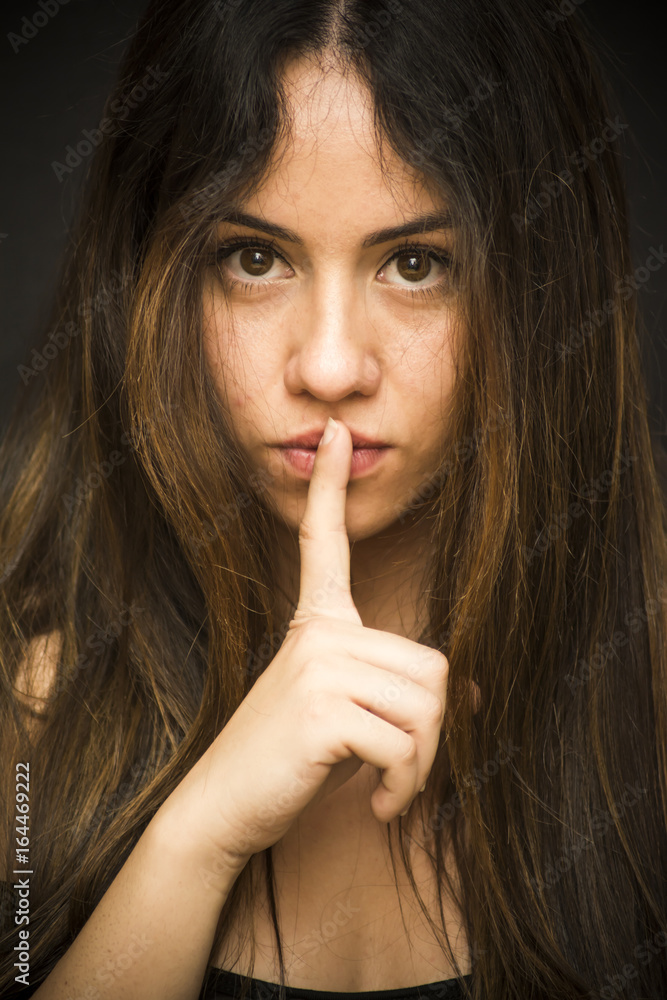 Portrait of a beautiful woman Commanding silence on black background Portrait of a beautiful woman Commanding silence on black background