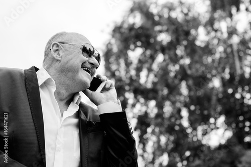 Mature stylish man in classic costume and sunglasses talk to telephone