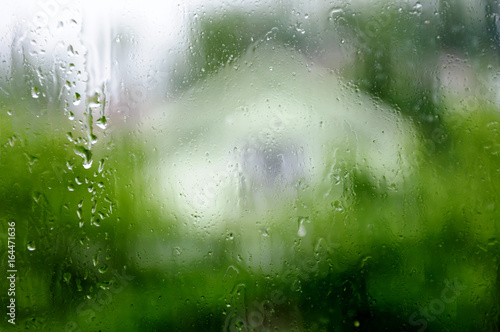 Wet window with drops, raining in a countryside