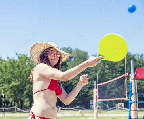 Young adult woman playing tennis on the beach