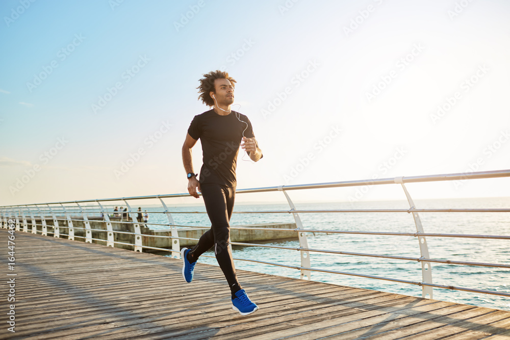 Φωτογραφία Attractive male athlete wearing stylish black sport clothing and blue sneakers