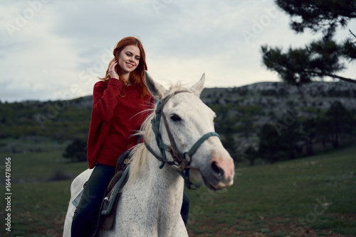 Beautiful young woman walking in the mountains with a horse