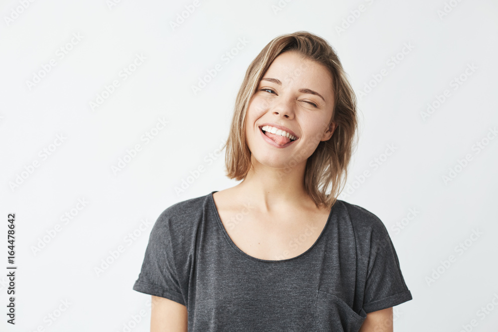 Funny cute young girl smiling winking showing tongue looking at camera over white background. Funny cute young girl smiling winking showing tongue looking at camera over white background.