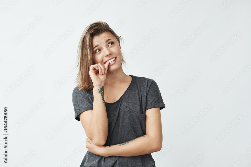 Nervous young pretty girl looking in side biting nails over white background. Nervous young pretty girl looking in side biting nails over white background.