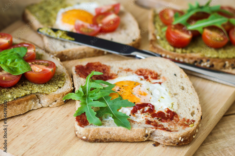 Healthy balanced toasts with egg, arugula, red cherry tomatoes, spinach leaves, pesto and tomato sauce and multicereal bread. Healthy breakfast sandwiches Healthy balanced toasts with egg, arugula, red cherry tomatoes, spinach leaves, pesto and tomato sauce and multicereal bread. Healthy breakfast sandwiches
