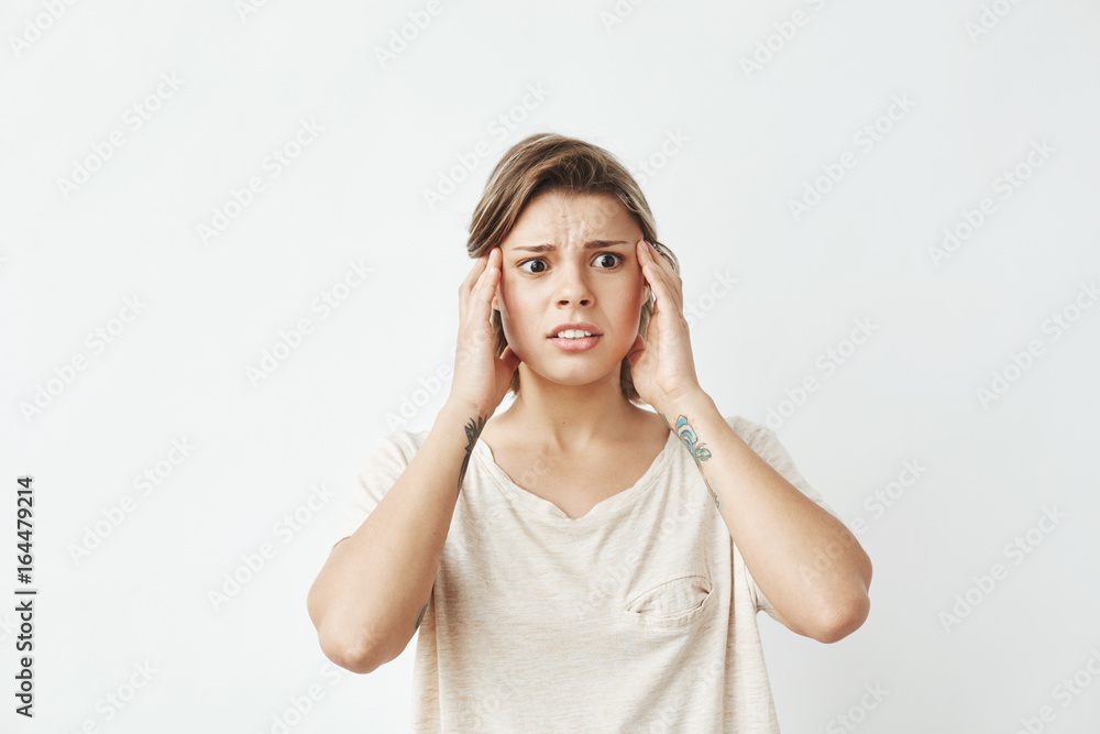 Young beautiful girl ashamed frowning with fingers on temples over white background. Young beautiful girl ashamed frowning with fingers on temples over white background.