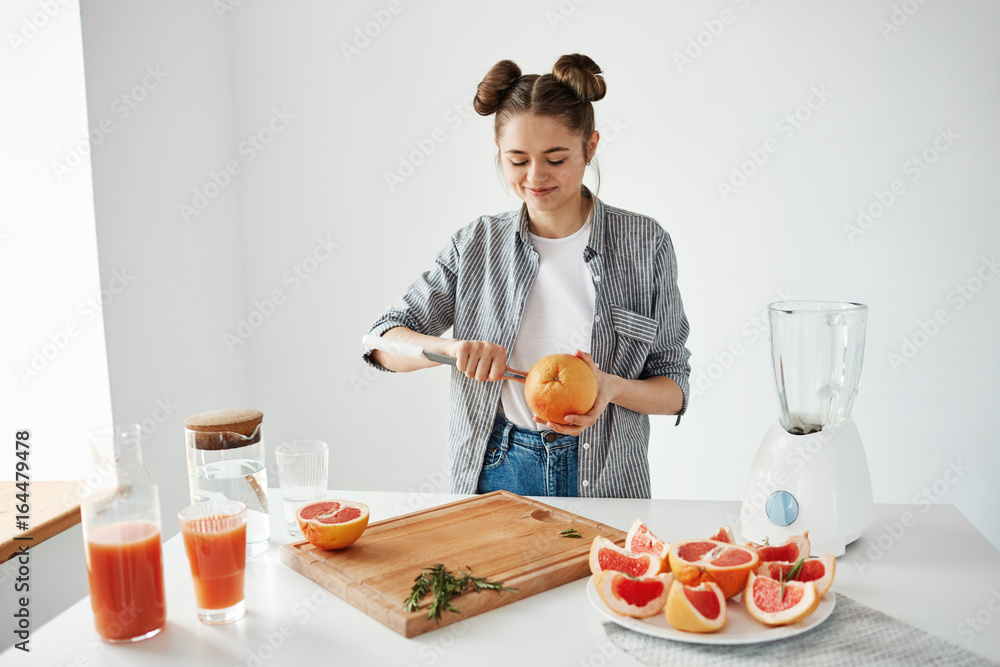 Girl making grapefruit juice or smoothie cutting fruits smiling. Healthy lefestyle concept.
