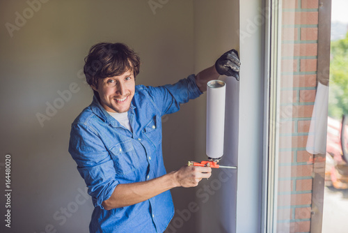 Man in a blue shirt does window installation photo