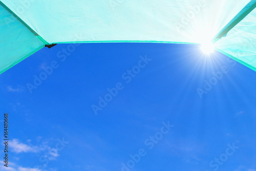 Blue sky with sun rays seen from inside a tent. Summer frame background concept. 