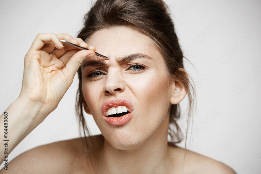 Young pretty girl with perfect clean skin
tweeze eyebrows making funny face over white background. Beauty and spa. Young pretty girl with perfect clean skin
tweeze eyebrows making funny face over white background. Beauty and spa.