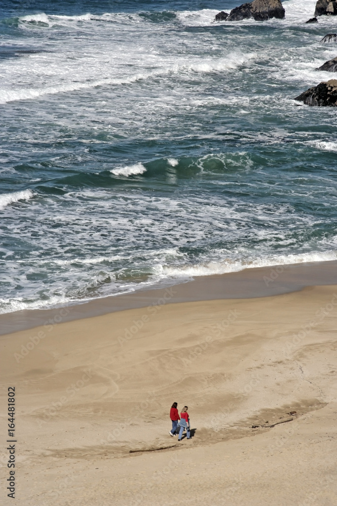 Female couple strolling on Pacific coast beach. High angle view. Female couple strolling on Pacific coast beach. High angle view.