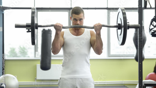 athlete doing exercise for biceps with barbell. young muscular man trains at the gym. crossfit training