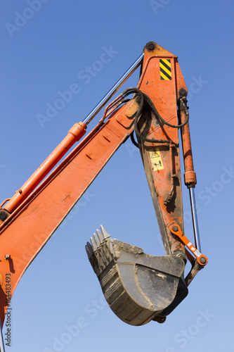 An orange excavator on a blue sky background photo