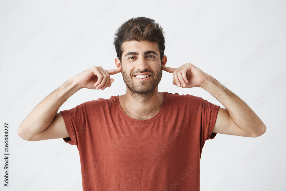 Portrait of annoyed young male Caucasian with eyes closed plugging his ears with fingers can't stand loud noise or ignoring stressful unpleasant situation or conflict. Negative human emotions. Portrait of annoyed young male Caucasian with eyes closed plugging his ears with fingers can't stand loud noise or ignoring stressful unpleasant situation or conflict. Negative human emotions.
