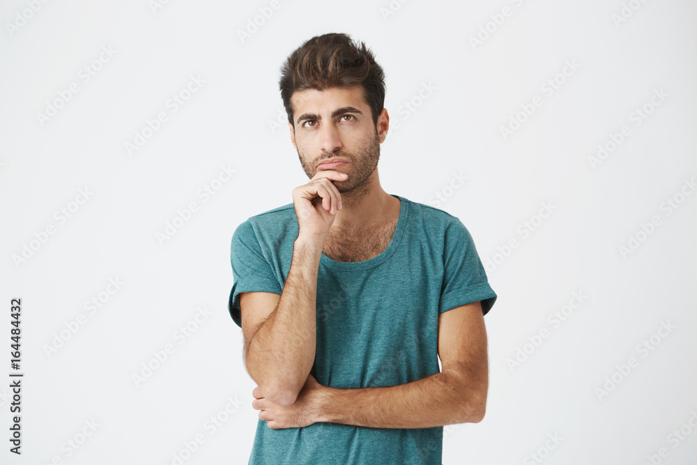 Fashionable, stylish man with dark eyes in casual clothes looking aside with placid and thoughtful look. Pensive guy with puzzled expression thinking about something or building plans. Fashionable, stylish man with dark eyes in casual clothes looking aside with placid and thoughtful look. Pensive guy with puzzled expression thinking about something or building plans.