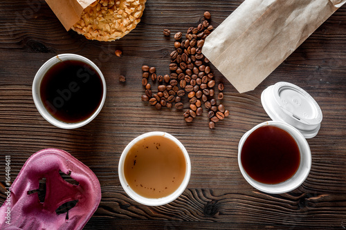 Coffee take out. Coffee cups with covers, coffee beans and cookies on wooden table backound top view photo