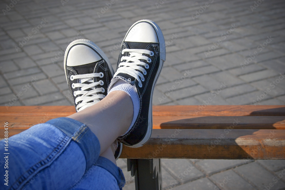 legs of a young girl in blue jeans and sneakers