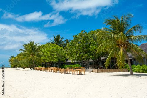 Wooden tables and chairs of tropical restaurant on the sand
