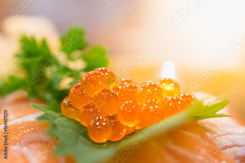 Close up of raw salmon roe / eggs is known as ikura on raw salmon sashimi - Japanese tradition food.
