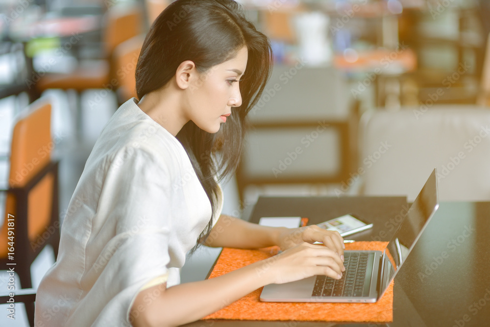 Fototapeta premium Young pretty business woman with laptop in the office, smiling pretty young business woman in glasses sitting on workplace. Selective focus