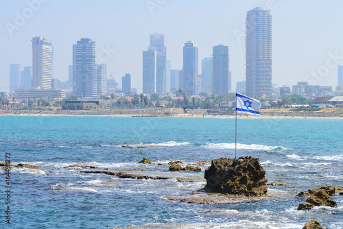 Obraz na płótnie TEL AVIV, ISRAEL - APRIL, 2017: The flag of Israel against the background of modern Tel Aviv, the Mediterranean Sea. w salonie