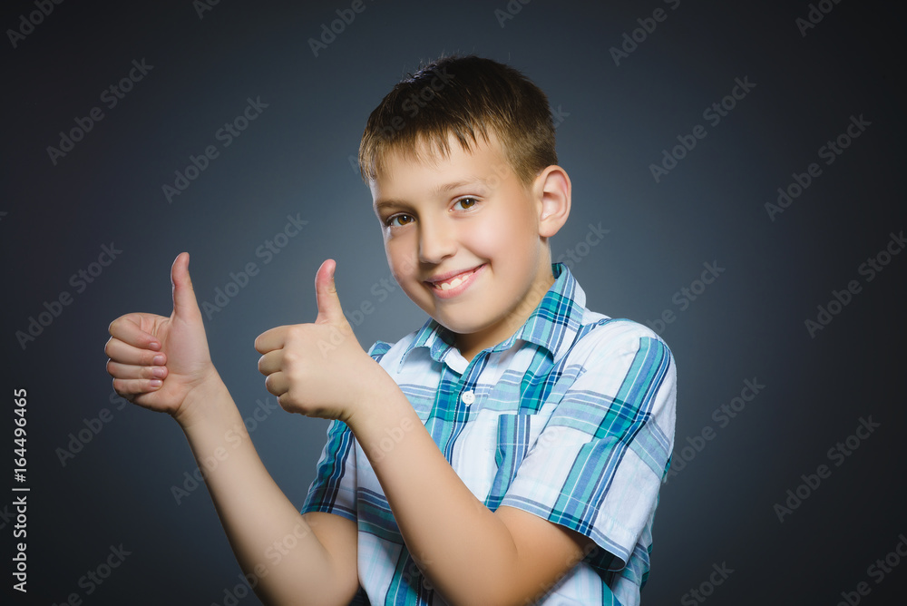 Closeup portrait successful happy boy show thumb up isolated grey background. Closeup portrait successful happy boy show thumb up isolated grey background.