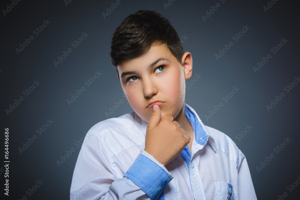 doubt, expression and people concept - boy thinking over gray background doubt, expression and people concept - boy thinking over gray background
