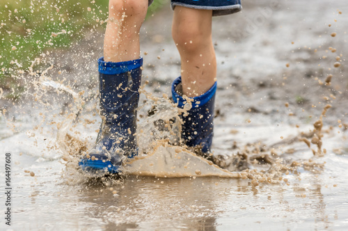 Kind rennt durch Regenpfütze