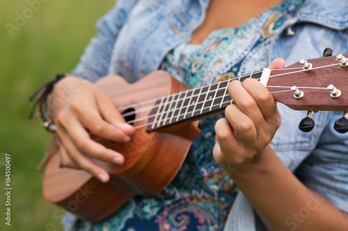 Young hipster woman playing on Ukulele outdoors