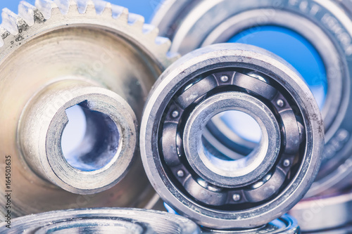 Group of various ball bearings and gears close up on nice blue background with reflections photo