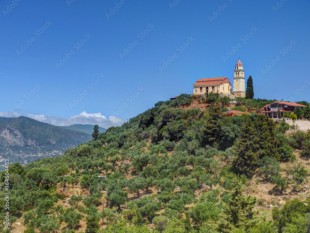 Beautiful view on orange roofing temple church on top of green hills mountains on Greece island Zakynth and blue sky. Greece landscape. Greece tourism holidays vacation tours. Beige church on hill