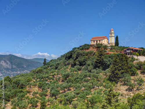 Beautiful view on orange roofing temple church on top of green hills mountains on Greece island Zakynth and blue sky. Greece landscape. Greece tourism holidays vacation tours. Beige church on hill