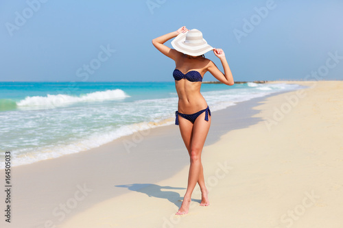 Sexy beautiful tanned woman relaxing and sunbathing in bikini on sea background and palm. Panoramic view from Jumeirah beach Dubai, UAE. Famous tourist destination. © oleg_p_100